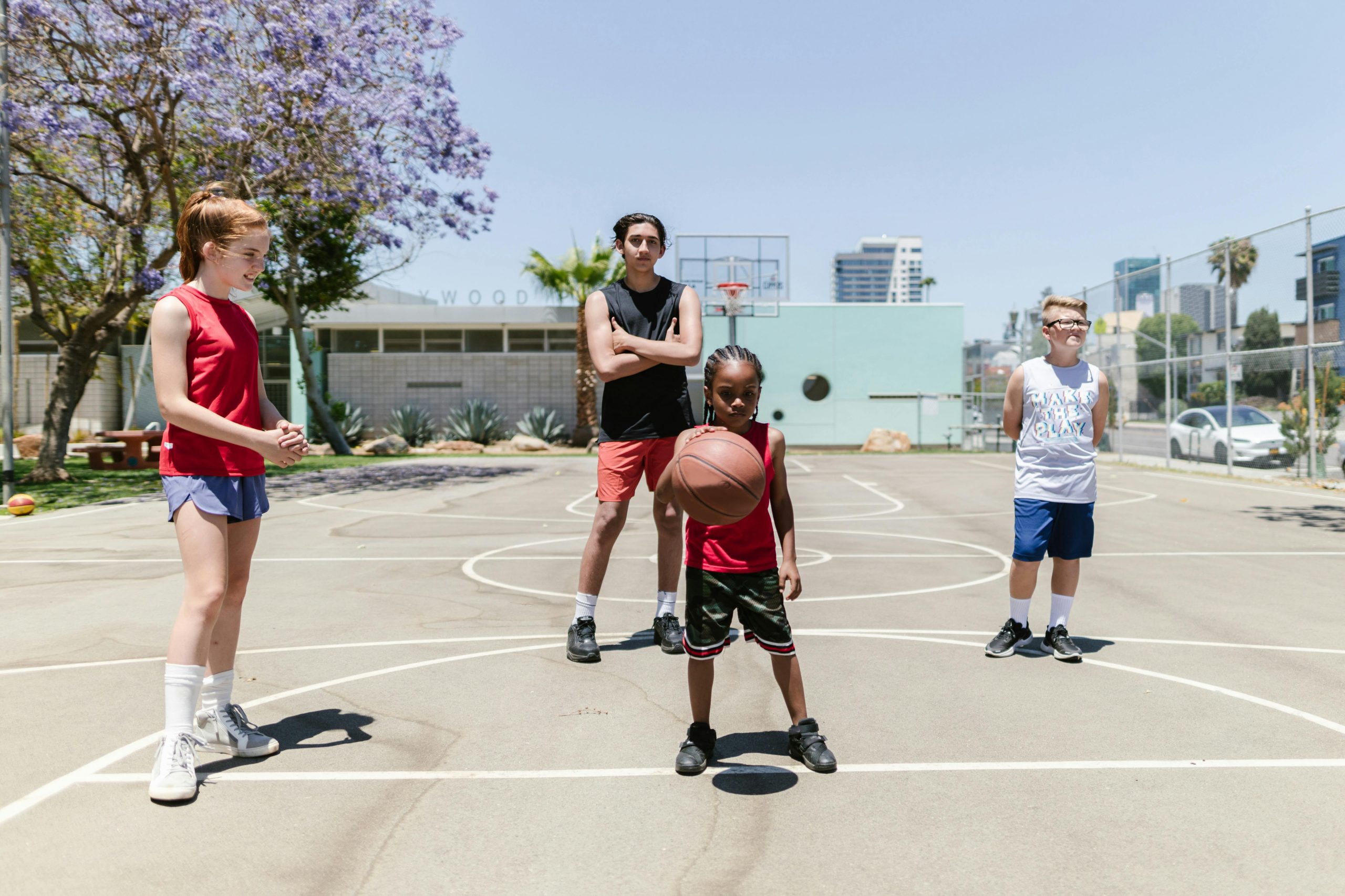 Group of kids enjoying a sunny day on the basketball court, showcasing sports and recreation.